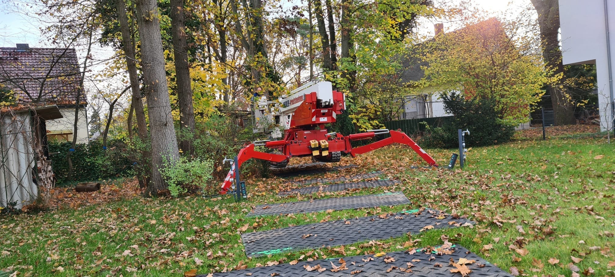 Kompakte Raupenarbeitsbühne in einem schmalen Garten